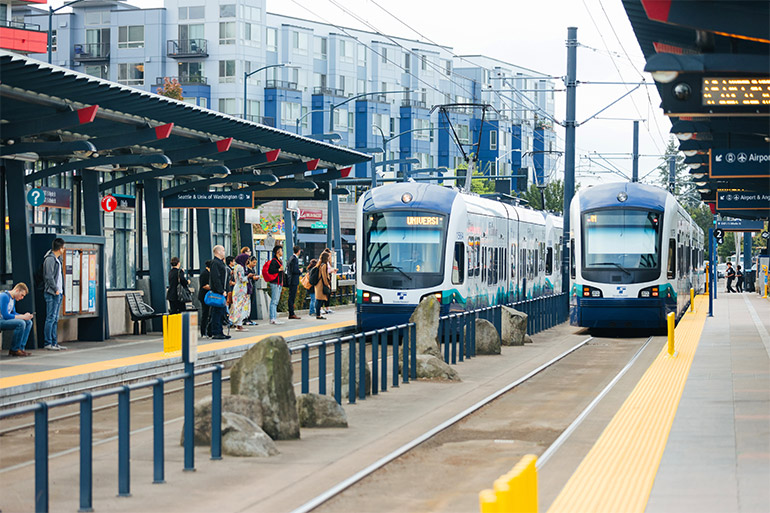 People wait at a Link Station to board two light rail trains.